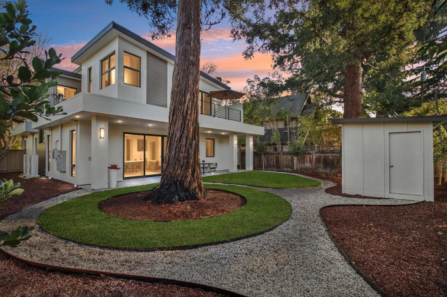 2200 Saint Francis Drive after preparation — the same rear garden at twilight, with lawn, gravel paths and planting around the redwood