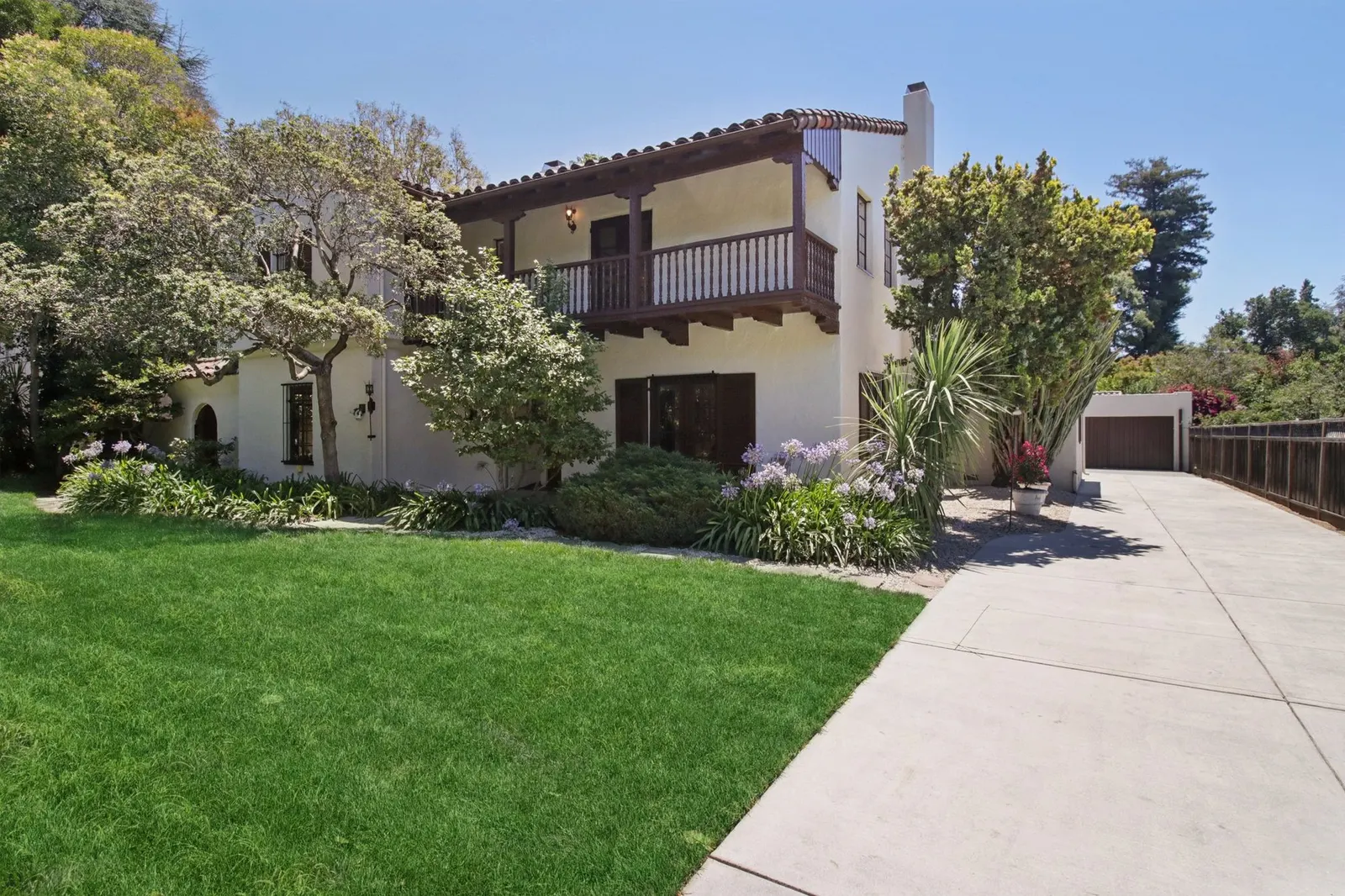 1560 University Avenue, Palo Alto — a Spanish-style family home with a balcony, mature trees and a lawn