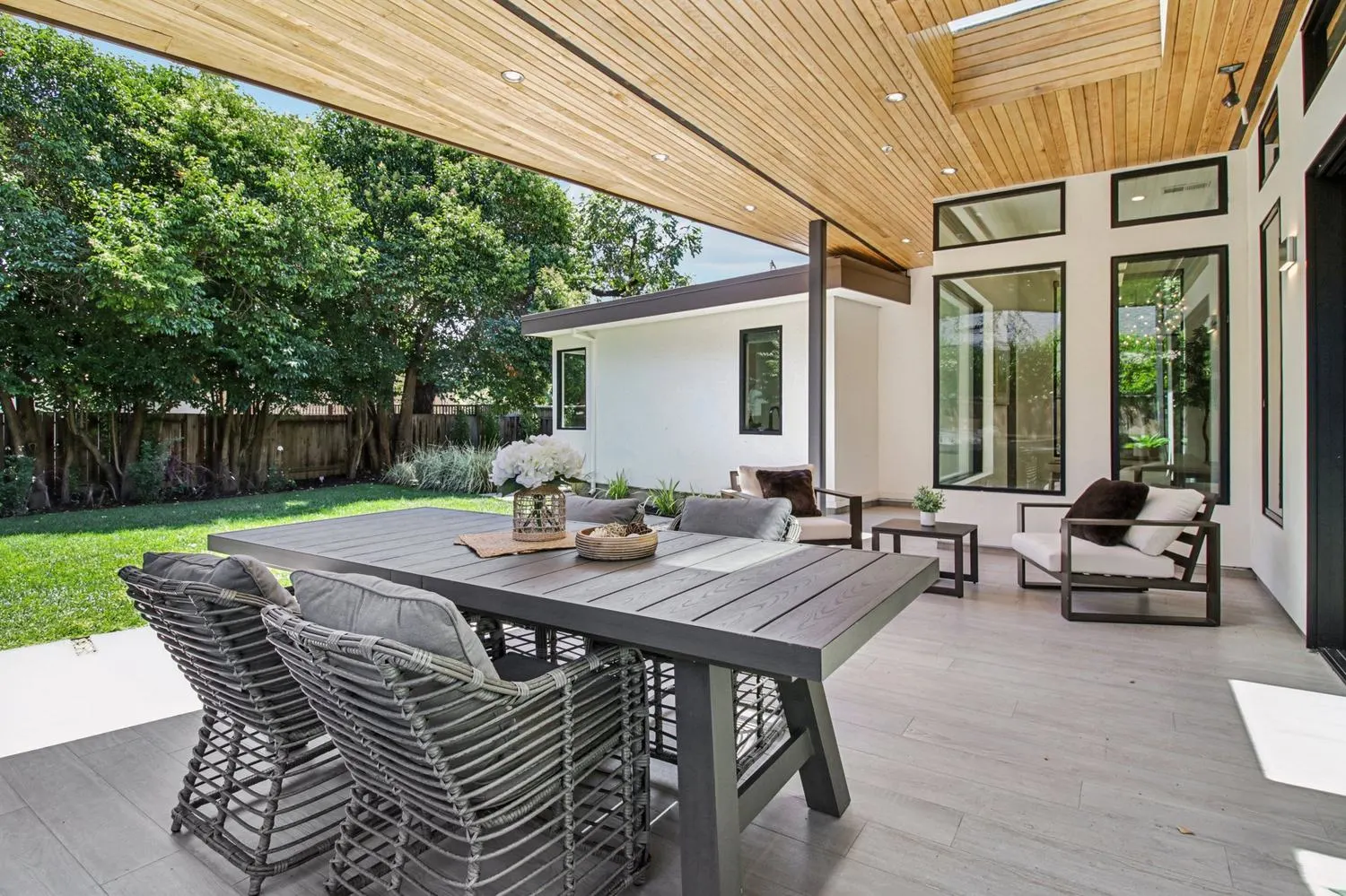 A covered terrace with a dining table, looking out over the lawn