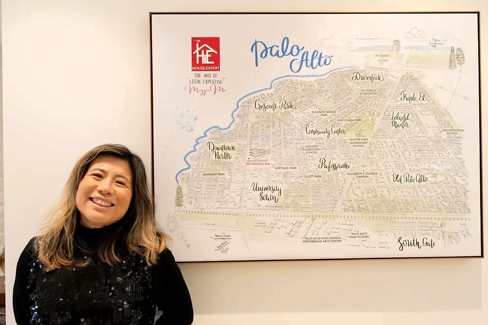 Maggie beside the framed hand-drawn map of the Palo Alto neighbourhoods on her office wall