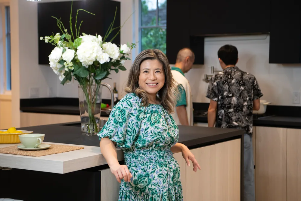 Maggie at the kitchen island during one of her open houses, visitors moving through behind her